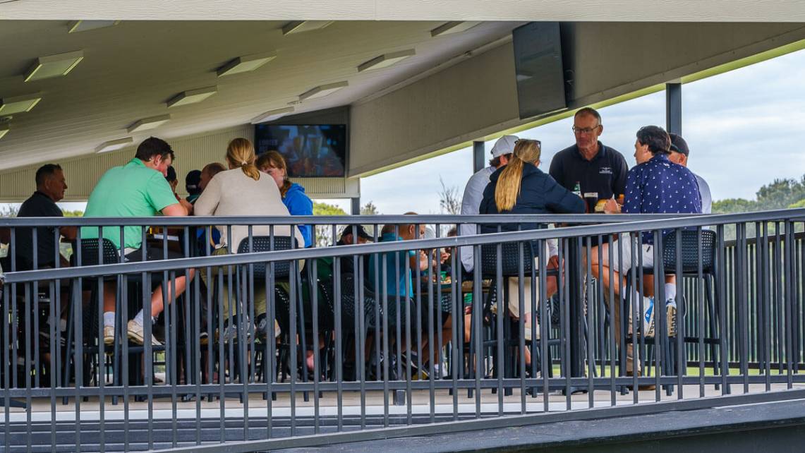 Lively clubhouse scene with members socialising on the balcony